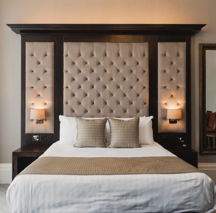 hotel room with large headboard and built in lamps