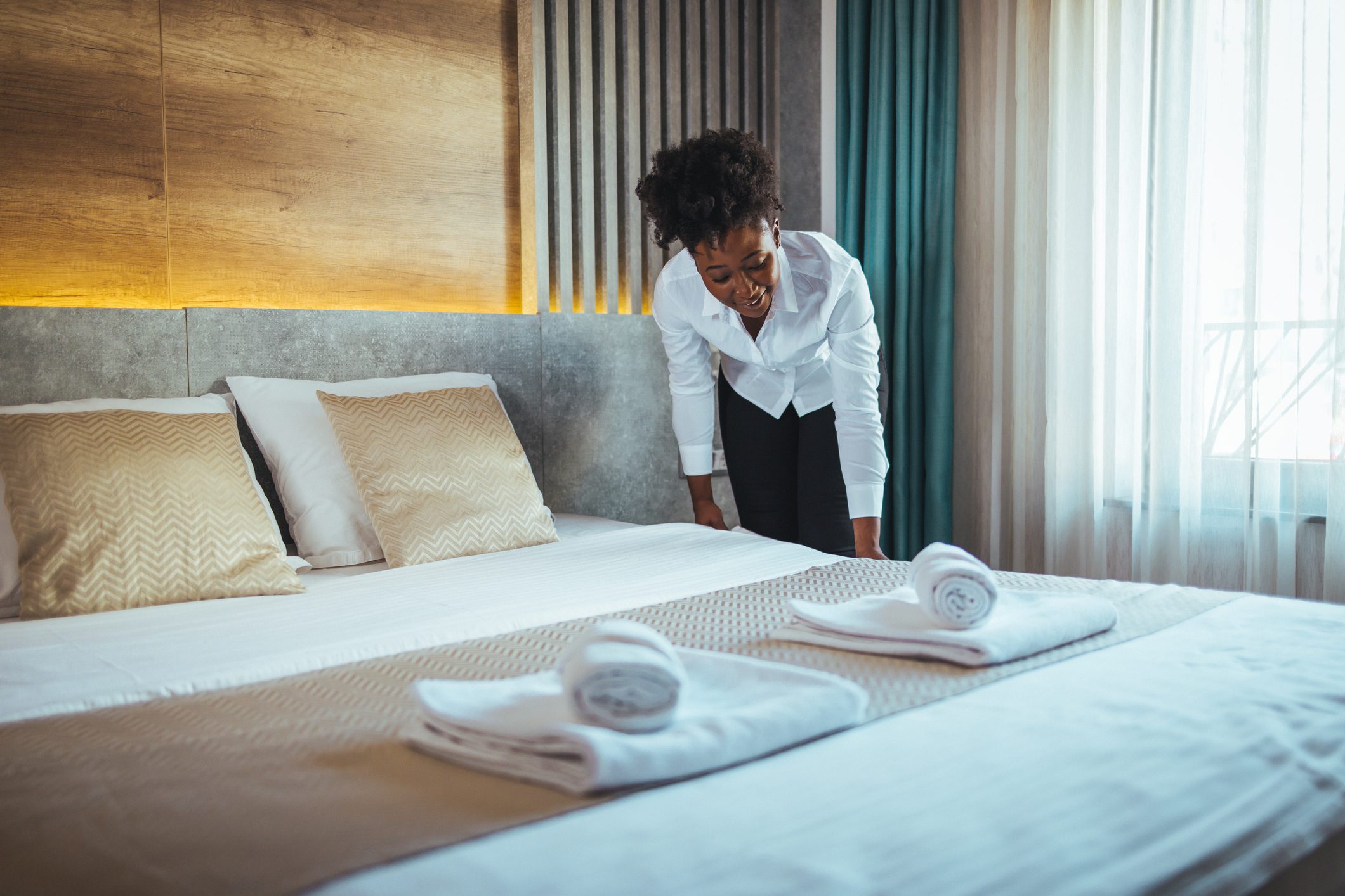 A woman making a bed in a hotel room