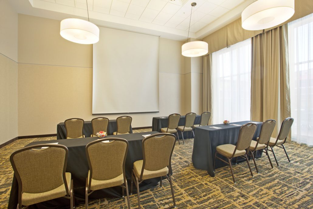 Hampton Inn & Suites conference room with tables, chairs, and a screen