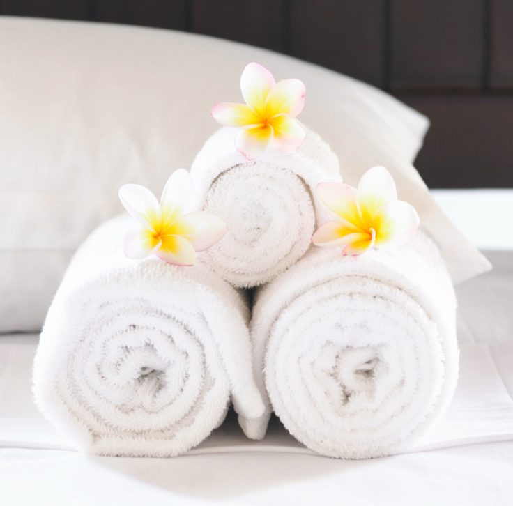 three white towels rolled up with flowers on each
