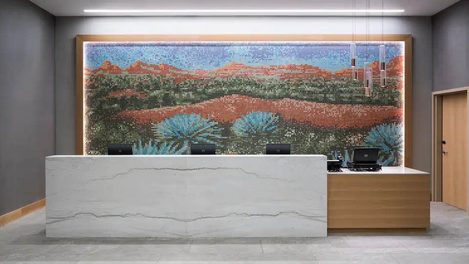 Hyatt House reception desk with a mosaic art piece behind the desk