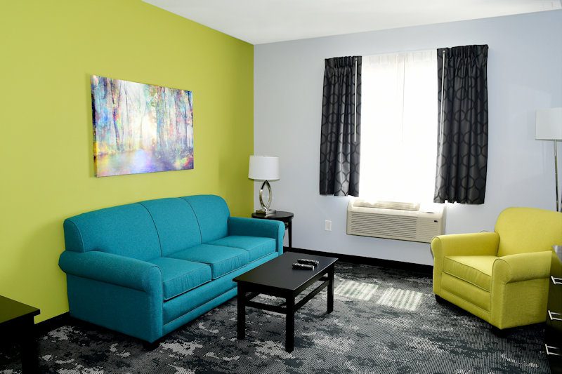 The Corning hotel room seating are with teal couch, lime green chair, and black coffee table