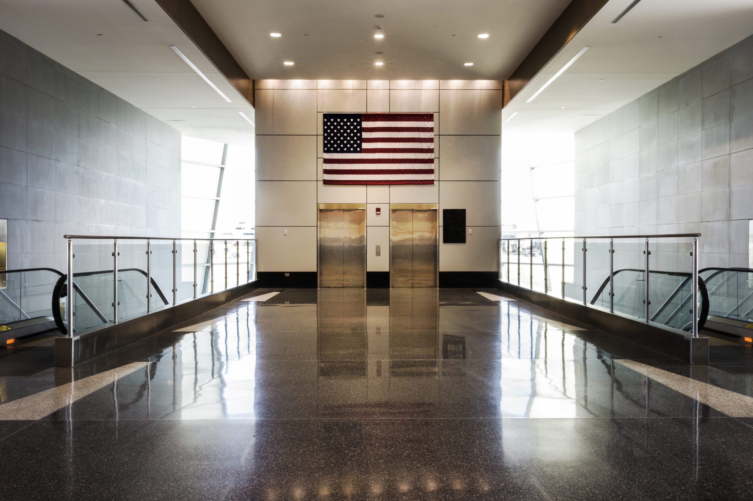 Interior of office building with an American flag over the entrance of two elevators