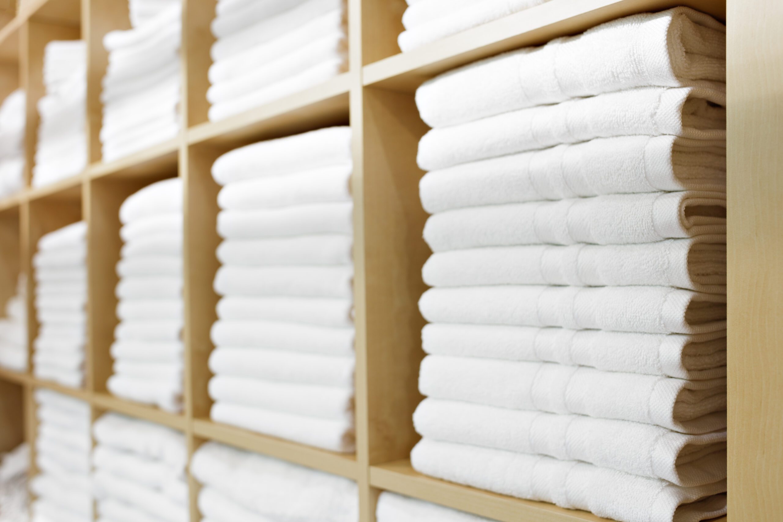 Fresh White Hotel Towels Folded and Stacked on a Shelf